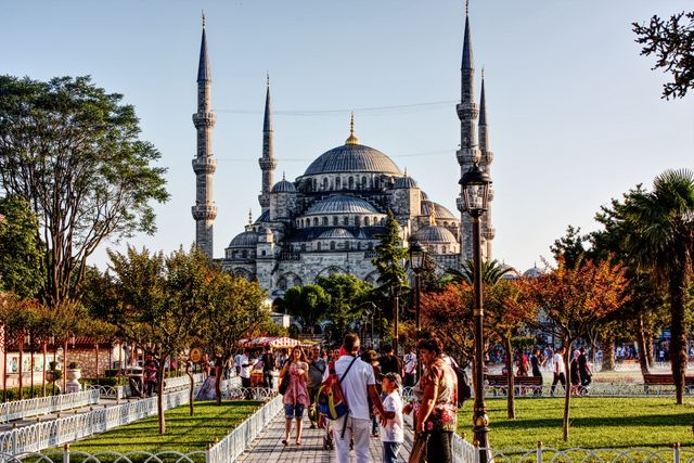 Vista de la Mezquita Azul de Estambul con sus minaretes y turistas caminando por los jardines de Sultanahmet.