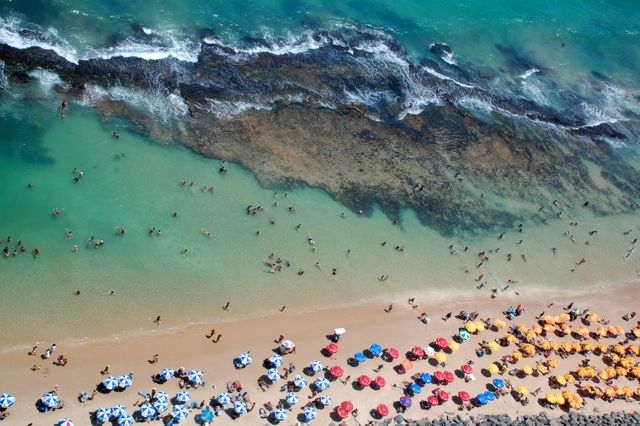Vista aérea de las piscinas naturales y arrecifes de Porto de Galinhas, en Pernambuco, con turistas bañándose junto a la playa.
