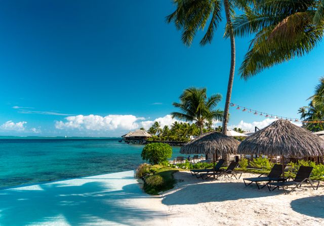 Playa tropical con palmeras, arena blanca y bungalows sobre el agua en la Polinesia Francesa