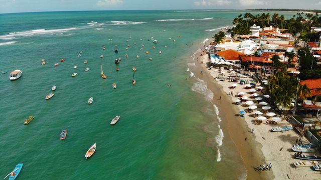 Vista aérea de la playa de Porto de Galinhas, en Pernambuco, con jangadas, aguas turquesas y la zona costera del pueblo.