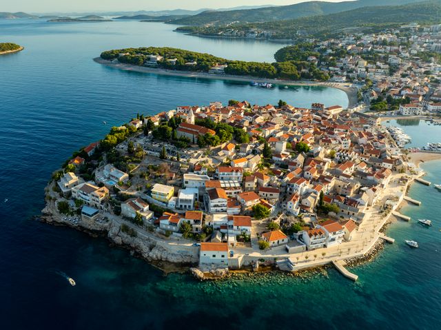 Vista aérea de Primošten, con su casco histórico de tejados rojos rodeado por las aguas del mar Adriático en Croacia.