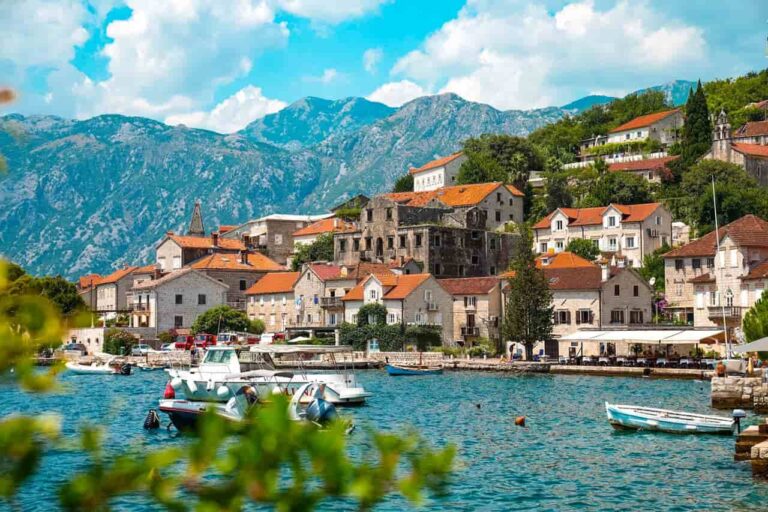 Pueblo costero de la bah&iacute;a de Kotor, en Montenegro, con casas de piedra, barcos y monta&ntilde;as junto al mar Adri&aacute;tico.