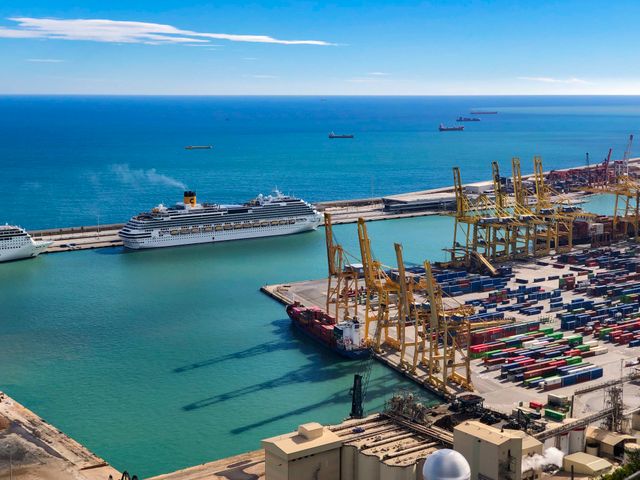 Vista aérea del Puerto de Barcelona con un crucero atracado, terminales portuarias y el mar Mediterráneo.