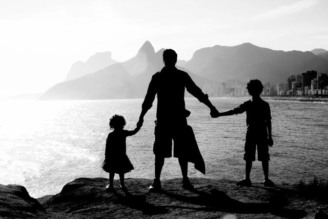 Padre con dos niños frente al mar en Río de Janeiro, con las playas de Ipanema y Leblon y el Morro Dois Irmãos al fondo.