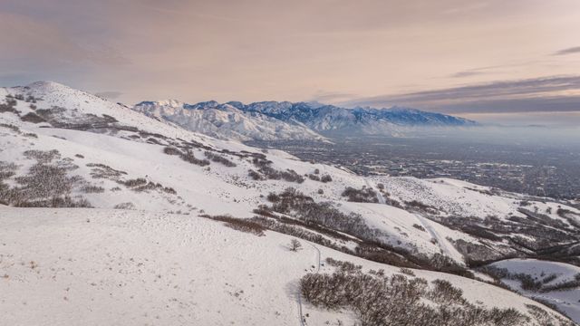 Montañas cubiertas de nieve con una ciudad al fondo durante el invierno cerca de Salt Lake City, Utah.