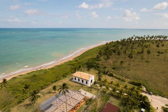 São Miguel dos Milagres, Brasil: playa y tranquilidad para jubilarse Vista aérea de São Miguel dos Milagres, Brasil, con playa, palmeras y una pequeña iglesia junto al mar