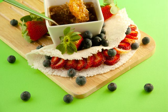 Tapioca brasileña rellena con fresas y arándanos, acompañada con miel.