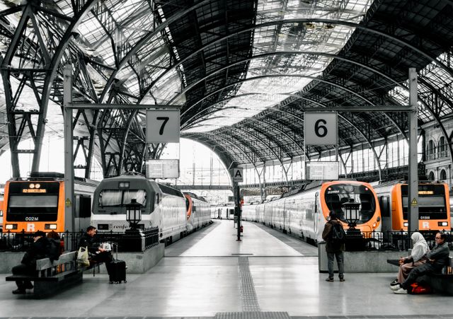 Trenes de Rodalies para moverse por Barcelona y alrededores Trenes de Rodalies y Renfe en una estación ferroviaria de Barcelona, con pasajeros esperando junto a los andenes.