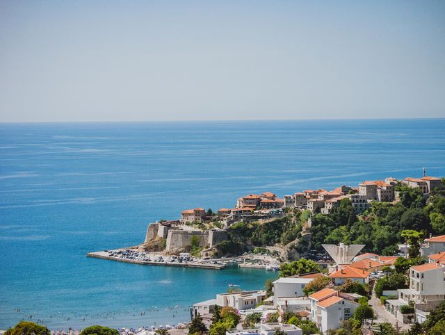 Vista del casco antiguo de Ulcinj junto al mar Adriático, con murallas, casas de tejados rojos y playas en la costa de Montenegro.