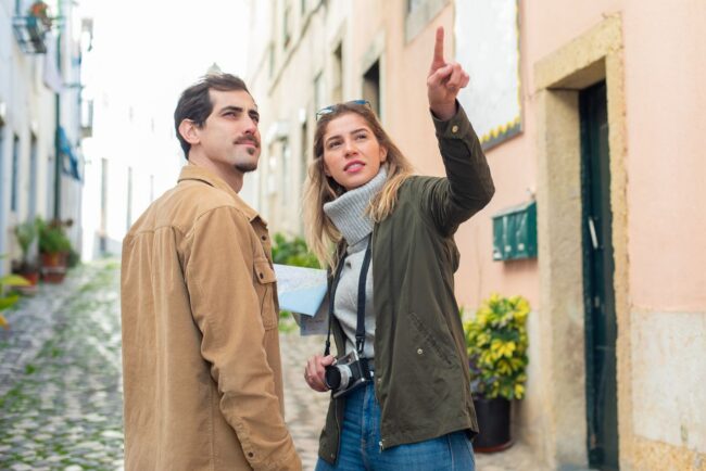 Dos turistas conversan y se&ntilde;alan un lugar mientras recorren una calle de una ciudad extranjera.