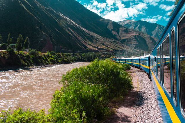 Tren panorámico recorriendo un valle de montaña junto a un río, imagen ideal para ilustrar viajes en tren emblemáticos del mundo.