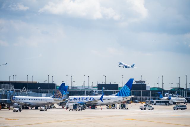 Aviones de United Airlines en una terminal de un aeropuerto de Estados Unidos mientras otra aeronave despega