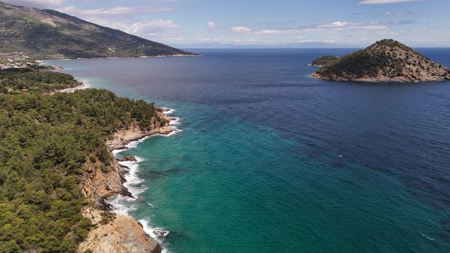 Vista de la costa de Alonissos, en Grecia, con aguas turquesa, bosque y una pequeña isla frente al mar