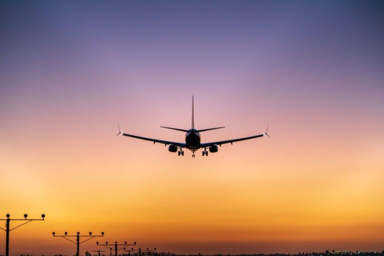 Avión comercial se aproxima a una pista de aterrizaje al atardecer