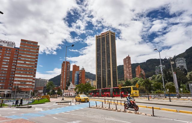 Vista urbana de Bogotá con edificios, transporte público y las montañas al fondo