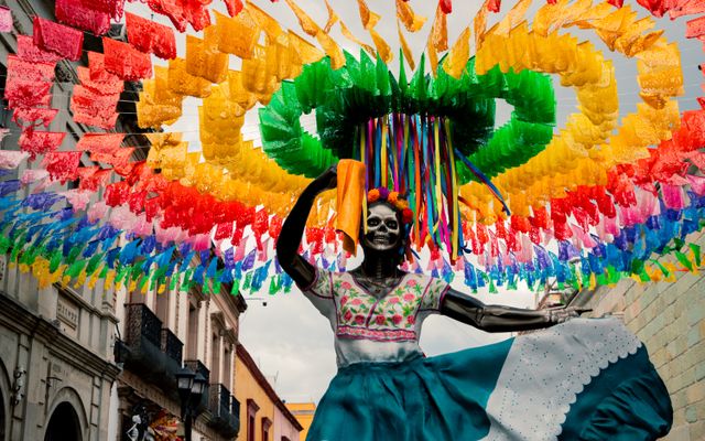 Figura de Catrina bajo papel picado de colores durante las celebraciones de Día de Muertos en Oaxaca