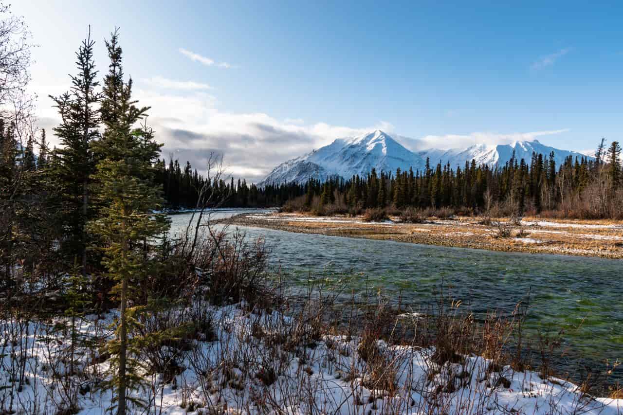 Río rodeado de bosque y montañas nevadas en un destino de naturaleza para viajar en 2027