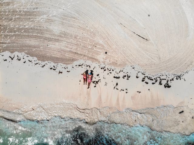 Great Exuma, en Bahamas, entre las islas más atractivas para viajar en 2026 Vista aérea de una playa de Great Exuma, en Bahamas, con arena clara, mar turquesa y dos personas descansando junto a la orilla