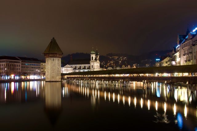 Puente de la Capilla y torre Wasserturm iluminados de noche en Lucerna, Suiza
