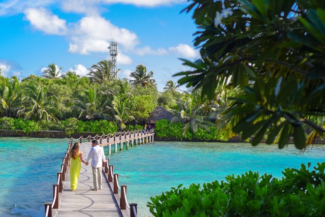 Mejor época para viajar a Maldivas y disfrutar de sus resorts Pareja camina por una pasarela sobre aguas turquesas en un resort de Maldivas
