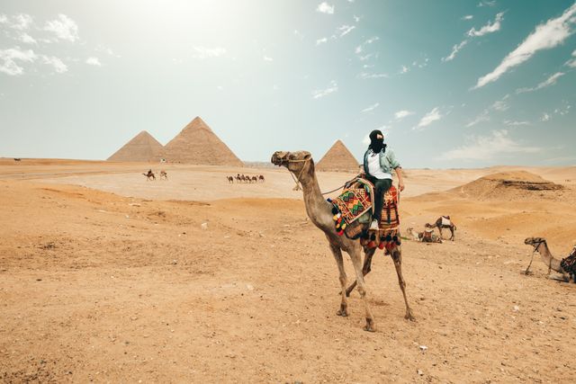 Mejor época para visitar las pirámides de Giza en Egipto Viajera en camello frente a las pirámides de Giza bajo el sol de Egipto