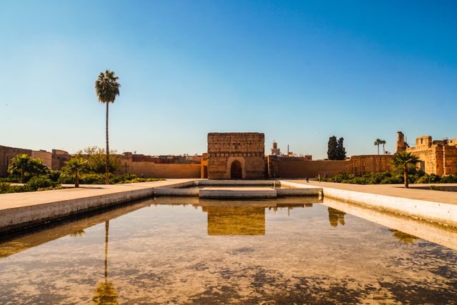 Palacio histórico de Marrakech bajo un cielo despejado, con palmeras y estanque central