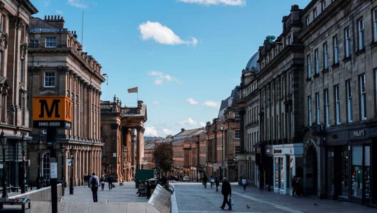 Grey Street en Newcastle upon Tyne, con edificios históricos, comercios y peatones en el centro de la ciudad
