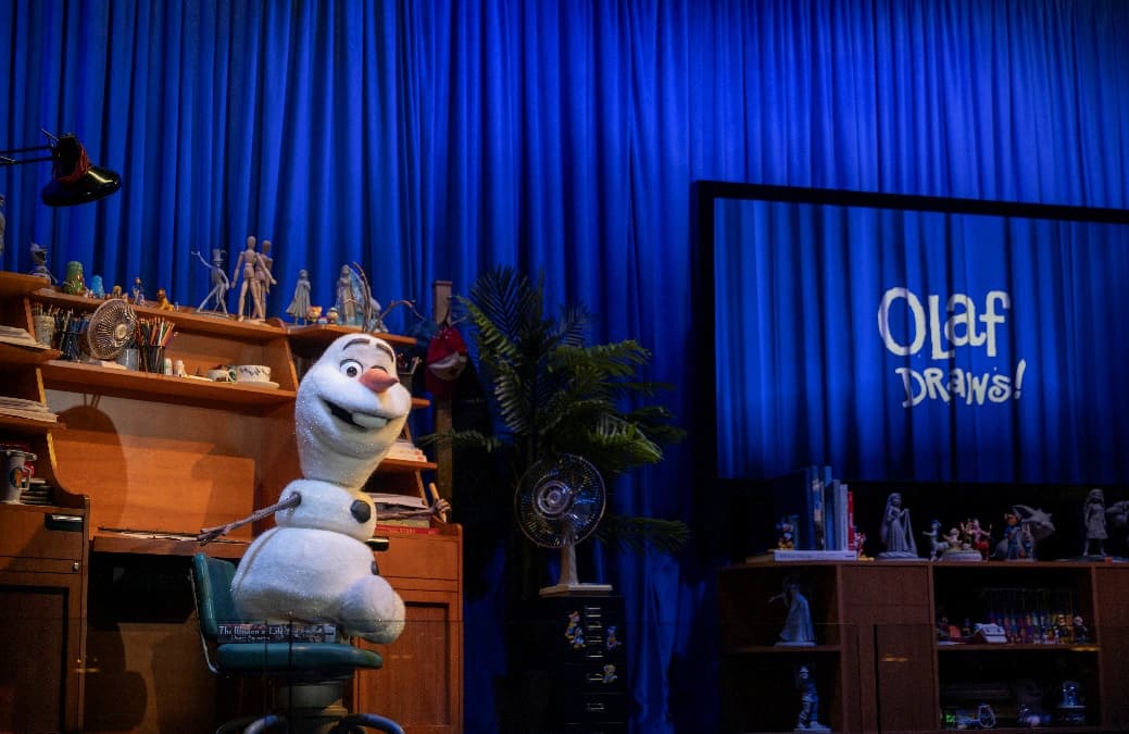 Olaf en la nueva experiencia de Disney Animation en Hollywood Studios junto a una pantalla con el mensaje Olaf Draws