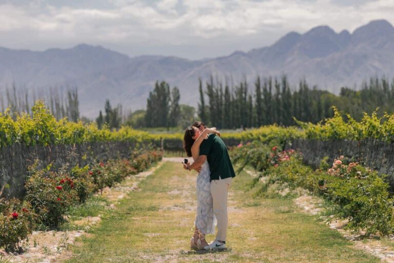 Pareja entre viñedos de Mendoza con montañas al fondo durante una visita a bodegas