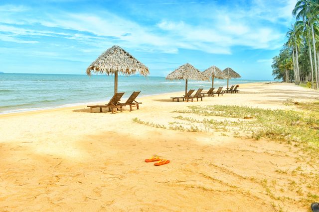 Playa tranquila con reposeras y sombrillas de paja, ideal para viajar en temporada baja