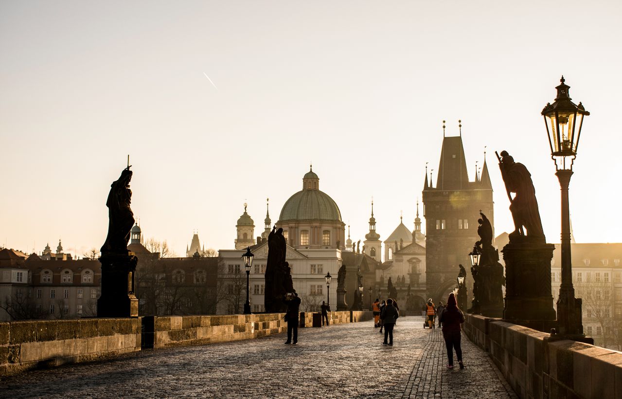 Puente de Carlos en Praga con sus estatuas y edificios históricos al amanecer
