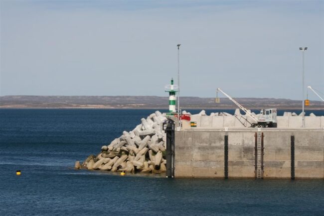Voluntariado en la Patagonia cerca de la costa Puerto de la Patagonia con escollera, faro y paisaje costero al fondo