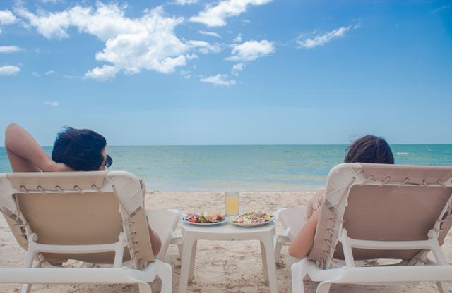 Resorts all inclusive en Estados Unidos para unas vacaciones diferentes Dos personas descansan en reposeras frente al mar en un resort de playa con comida y bebidas