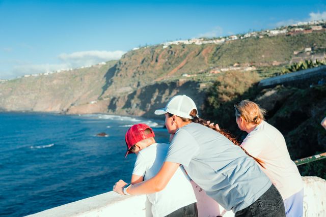 Familia contempla el mar y los acantilados desde un mirador costero durante un viaje con niños