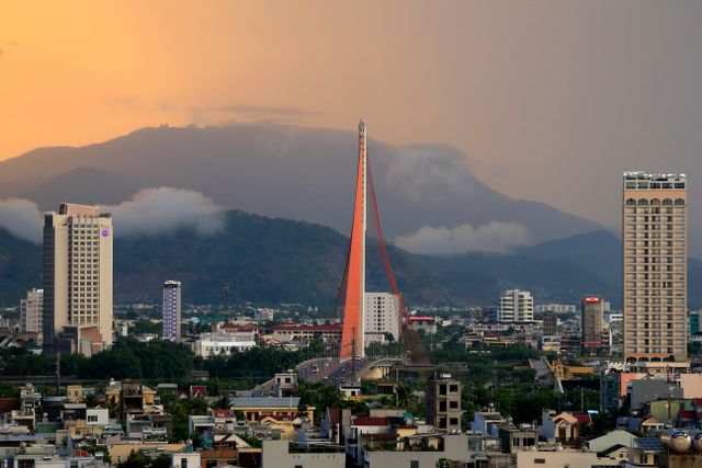 Vista urbana de Da Nang, Vietnam, con puente moderno y montañas cubiertas de nubes al fondo