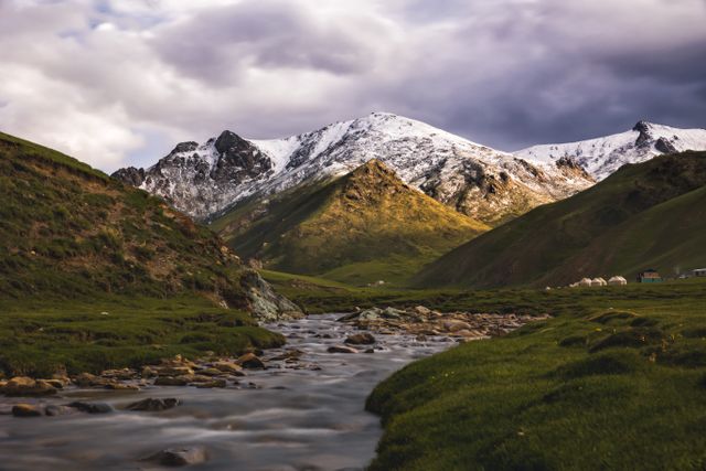 Kirguistán, uno de los destinos más subestimados para viajar en 2026 Paisaje de Kirguistán con montañas nevadas, valle verde, río y yurtas tradicionales