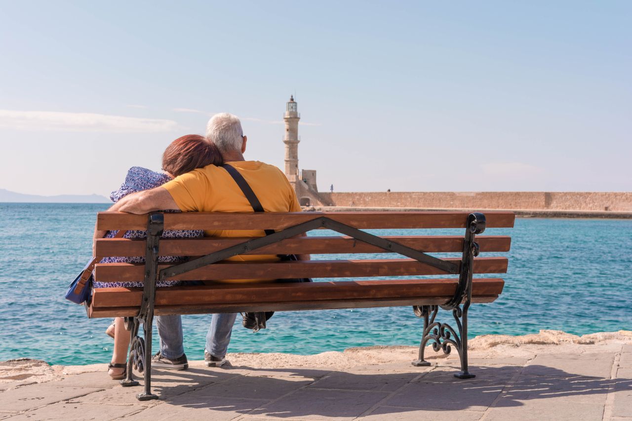 Pareja mayor sentada frente al mar durante una jornada tranquila junto a la costa