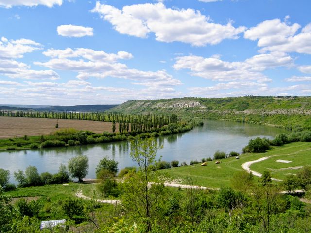 Moldavia, uno de los destinos más subestimados para viajar en 2026 Paisaje rural de Moldavia con río, campos verdes y colinas bajo un cielo despejado