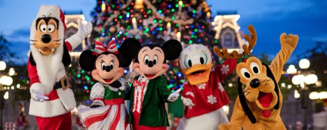 Mickey, Minnie, Donald, Goofy y Pluto con vestuario navideño frente a un árbol de Navidad en Disney World