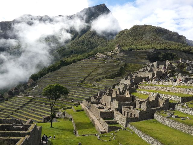 Terrazas y construcciones de piedra de Machu Picchu entre montañas cubiertas de nubes en Perú