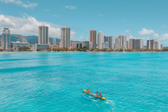Waikiki en Honolulu: cuándo conviene viajar a Hawaii Vista de Waikiki en Honolulu desde el mar, con edificios frente a la costa y una canoa sobre aguas turquesas